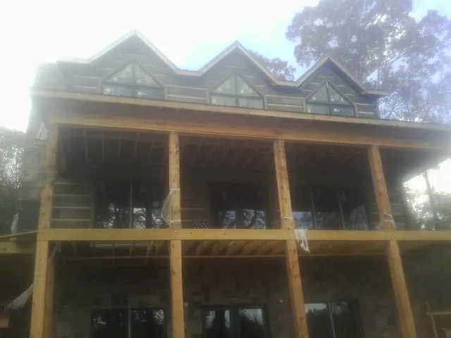 Dormers and porch framing on a large log home under construction — Roof Coating work by our crew in Princeton